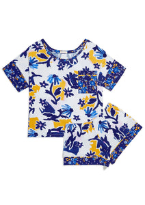 Flat lay. Matching Alex Pajama Set in the Alivia Whimsical Floral print which features scattered light and dark blue wildflowers with yellow shading on a white background. The classic men’s pajama style features a short sleeve boxy top with a scoop neckline, and loose-fitting shorts.
