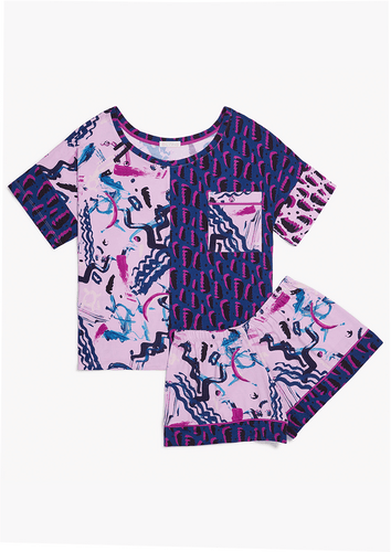 Flat lay. The Alex Pajama Set in Alivia Happy Strokes Pink features contrasting retro 80s prints. The left top panel and right shirt sleeve cuff have a lack, fuchsia, and blue leopard-style pattern. The right top panel and accent pocket have an abstract design of overlapping black, blue, and pink brush strokes on a pale pink background. The shorts have the abstract pale pink pattern with blue leg bands with fuchsia piping details at the cuff top.