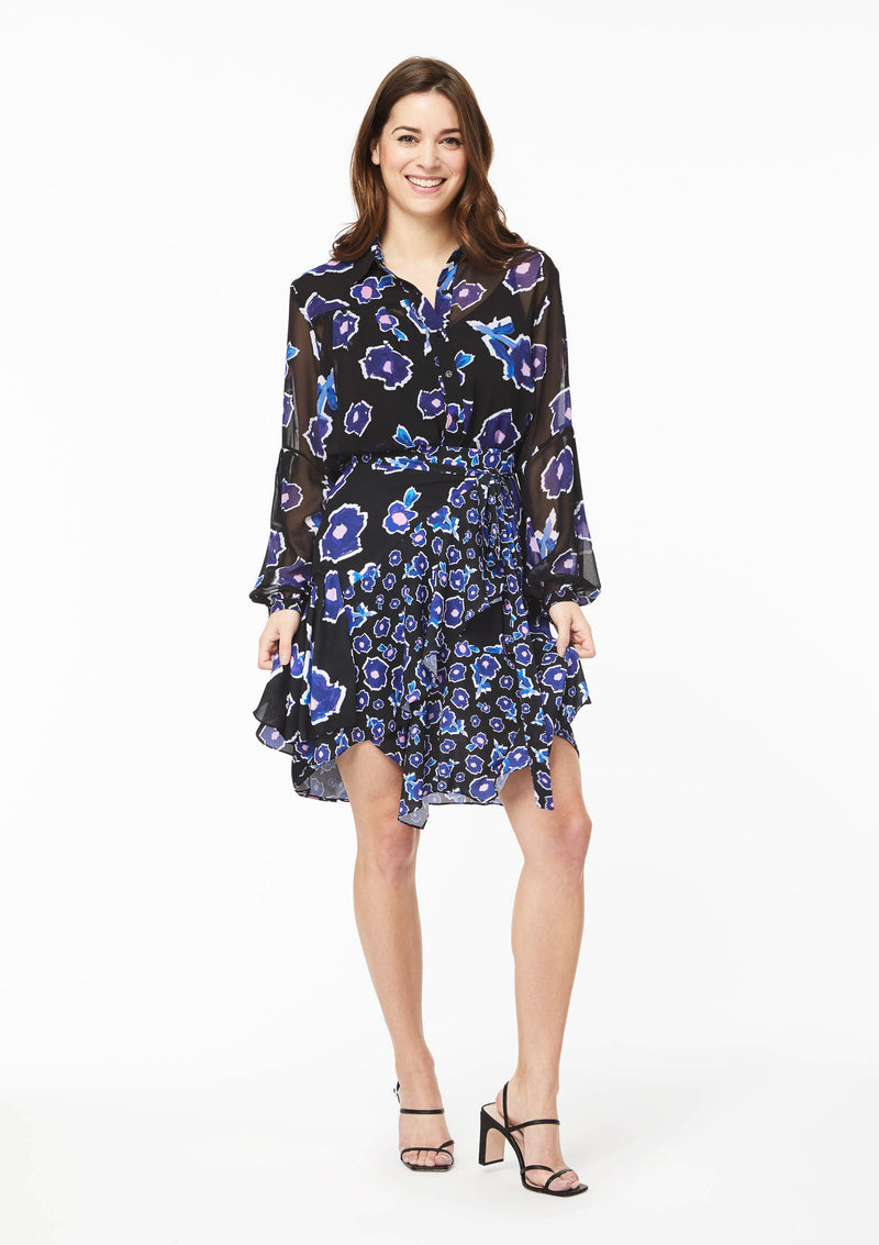 Front view. The Alivia Vicki Shirt in Poppy Play Black paired with the Gabi Skirt in Poppy Play Black and black strappy sandals. The shirt is tucked into the waistline of theskirt, creating the effect of a flowy dress with a cinched waist.