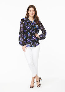 Front view showing full outfit pairing. The Poppy Play Black button-down blouse has been paired with white ankle-length straight-leg jeans and black strappy heels. The model’s hand is on their hip, showing that the blouse has a comfortable, loose fit around the waist, chest, arms, and shoulders.