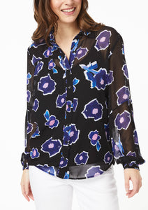 Closeup front view. Vicky Shirt in Poppy Play Black. The top 2 buttons are undone, creating a v-neckline that ends just above the black camisole, collar falling naturally to either side. Lined cuffs at the end of the sleeves have a snug fit around the hand with the blouson sleeve draping down and slightly overlapping the cuff.