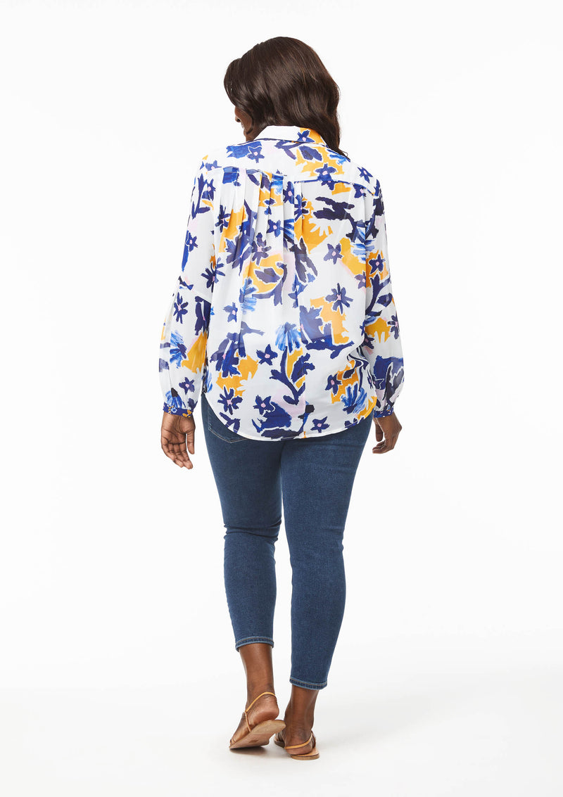Back view of the Vicki Shirt in Alivia’s Whimsical Floral. The fabric is sheer but almost appears opaque compared to the Poppy Play Black. The shirt hangs naturally around the pleats below the yoke seam. The tail of the shirt hangs down below the back pockets of the blue jeans.