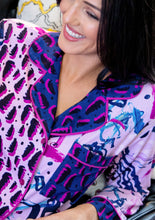 Load image into Gallery viewer, A closeup on the collar, lapel, and pocket of the Happy Strokes Pink Alivia Sofia Pajama Set. The abstract leopard-style fabric design matches the right front panel of the shirt,but the background color is sapphire blue with black and fuchsiasquiggles and dots instead of pink.