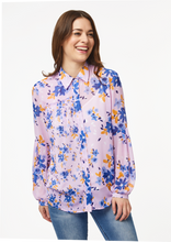 Load image into Gallery viewer, A person models the closeup front view of the Vicki Shirt in Wildflower Burst Orchid. The model’s arms are resting at their sides and the shirt is buttoned all the way to the top, creating a clean v-line at the base of the neck.
