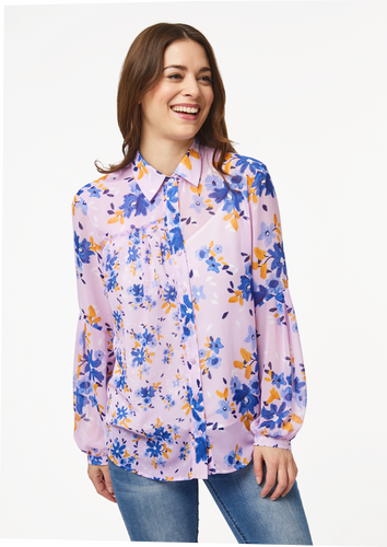 A person models the closeup front view of the Vicki Shirt in Wildflower Burst Orchid. The model’s arms are resting at their sides and the shirt is buttoned all the way to the top, creating a clean v-line at the base of the neck.